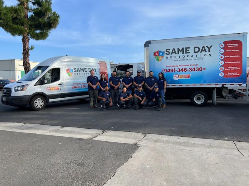 same day restoration team standing in front of branded vehicles