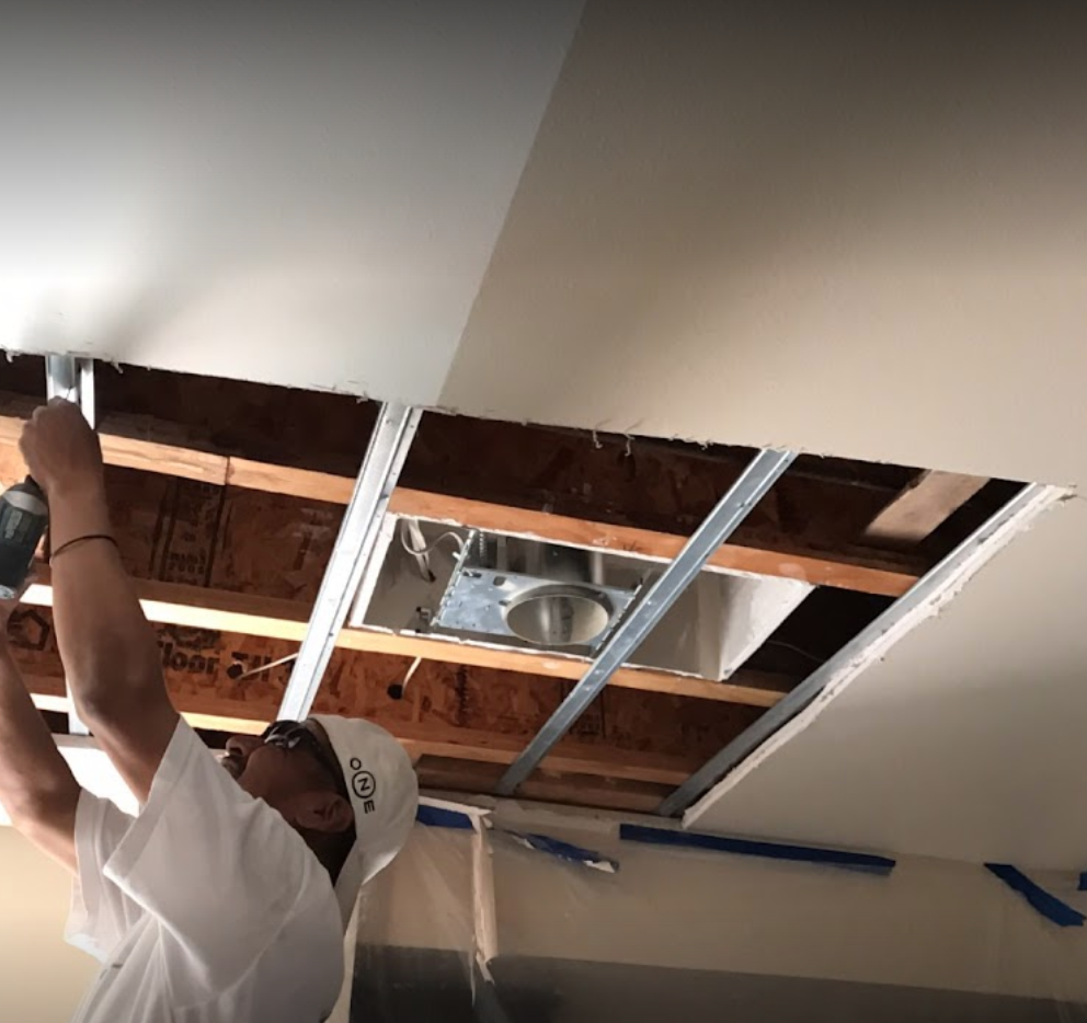 man tearing up ceiling in attic to find water damage