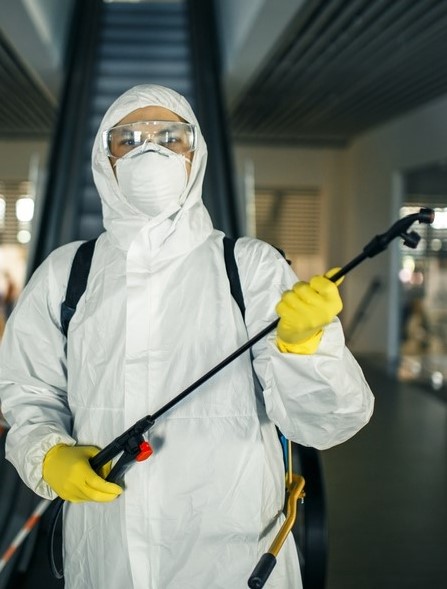 A man in a sanitizing disifection suit holding spray near the escalator to remove mold in California mall